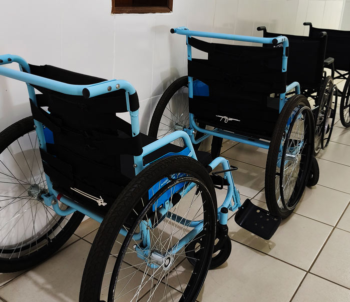 Two blue wheelchairs with black seats and large rear wheels parked indoors on a tiled floor.