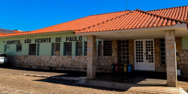 Exterior view of Hospital São Vicente de Paulo: stone-walled hospital with an orange tile roof, a covered entrance, and a blue sky above.